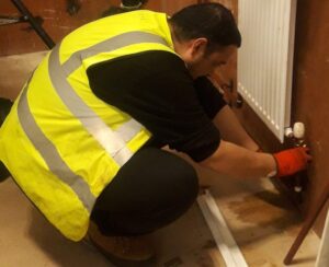 Owner in a yellow vest fixing a radiator