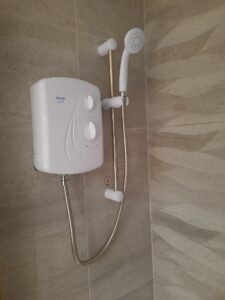 a white electric shower with a hose attached