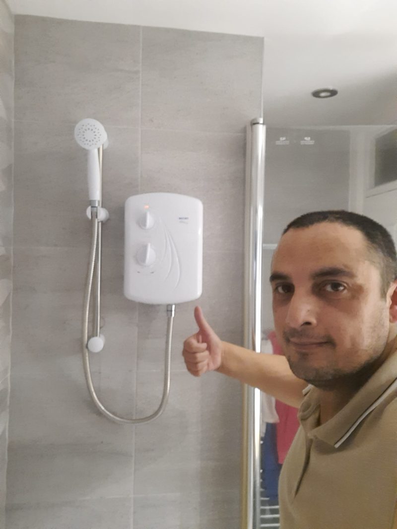 The owner giving a thumbs up in front of a newly installed shower